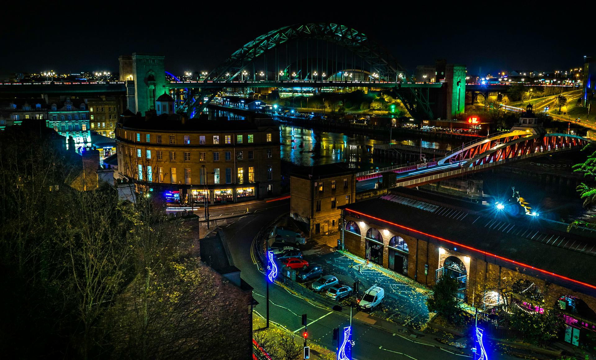 Aerial view of Newcastle Quayside at night with illuminated bridges and cityscape lights.