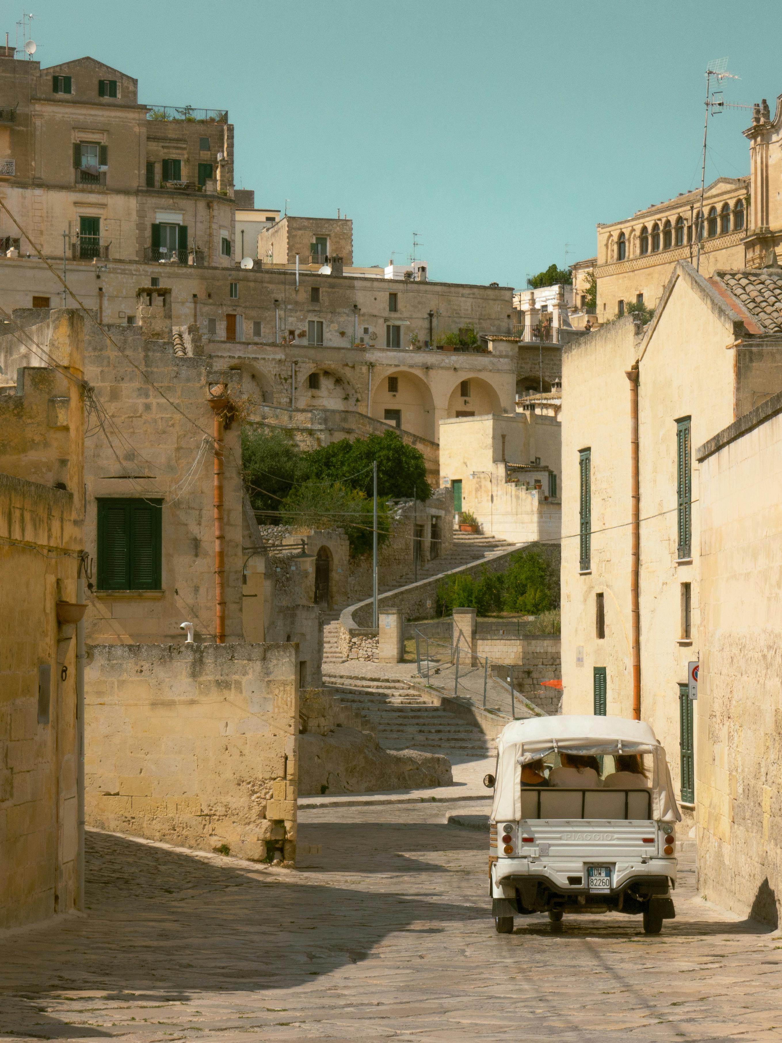Vintage car on a stone-paved street in Matera, capturing historic architecture.