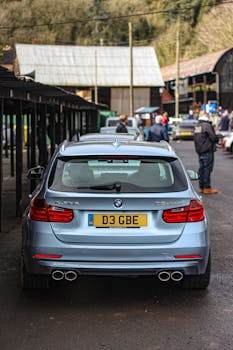 A light blue BMW Alpina D3 sedan parked on a bustling city street.
