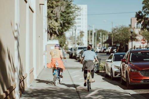 Two people riding bikes down a city street
