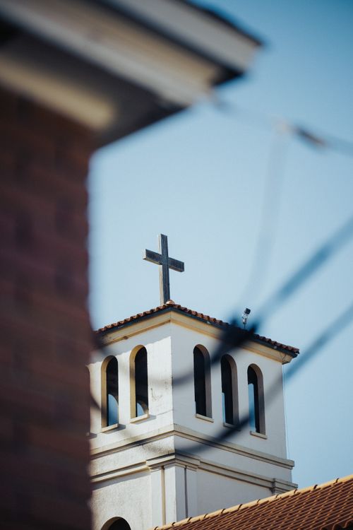 Free A church bell tower with cross stands tall against a clear blue sky, symbolizing faith. Stock Photo