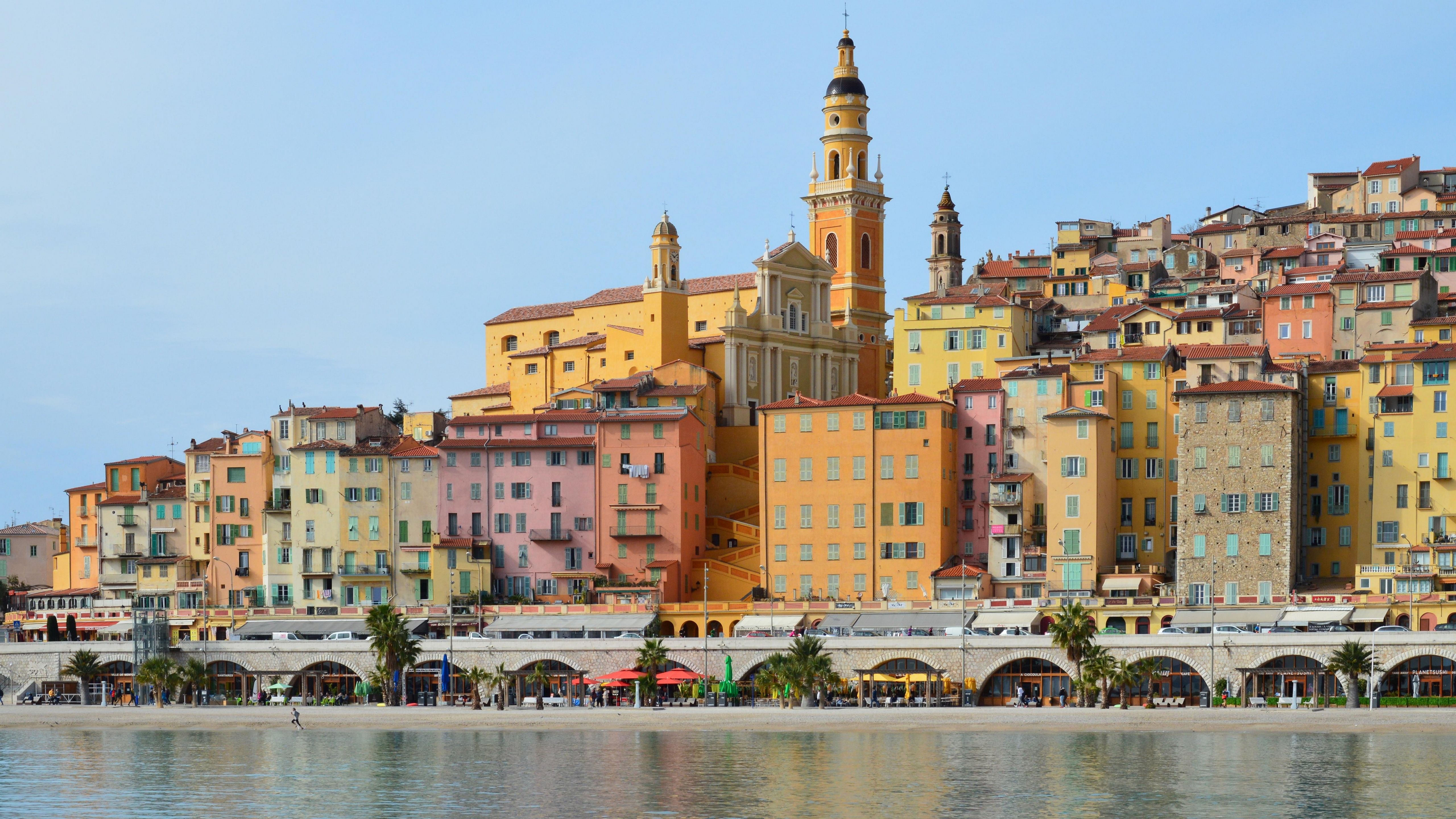 Picturesque coastal town featuring colorful buildings and a historic church by the sea.