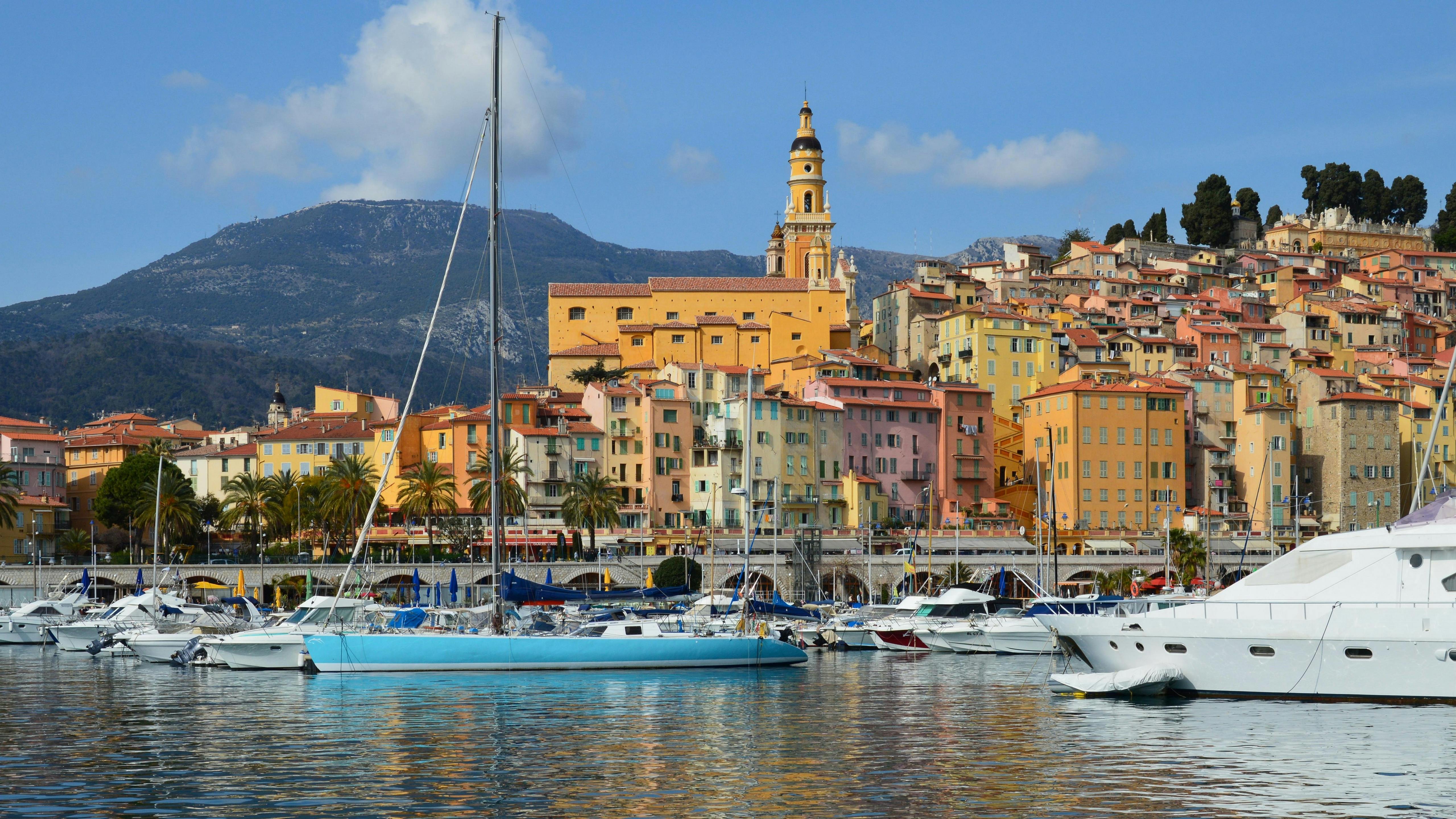 Beautiful harbor with sailboats and colorful buildings against a mountain backdrop.