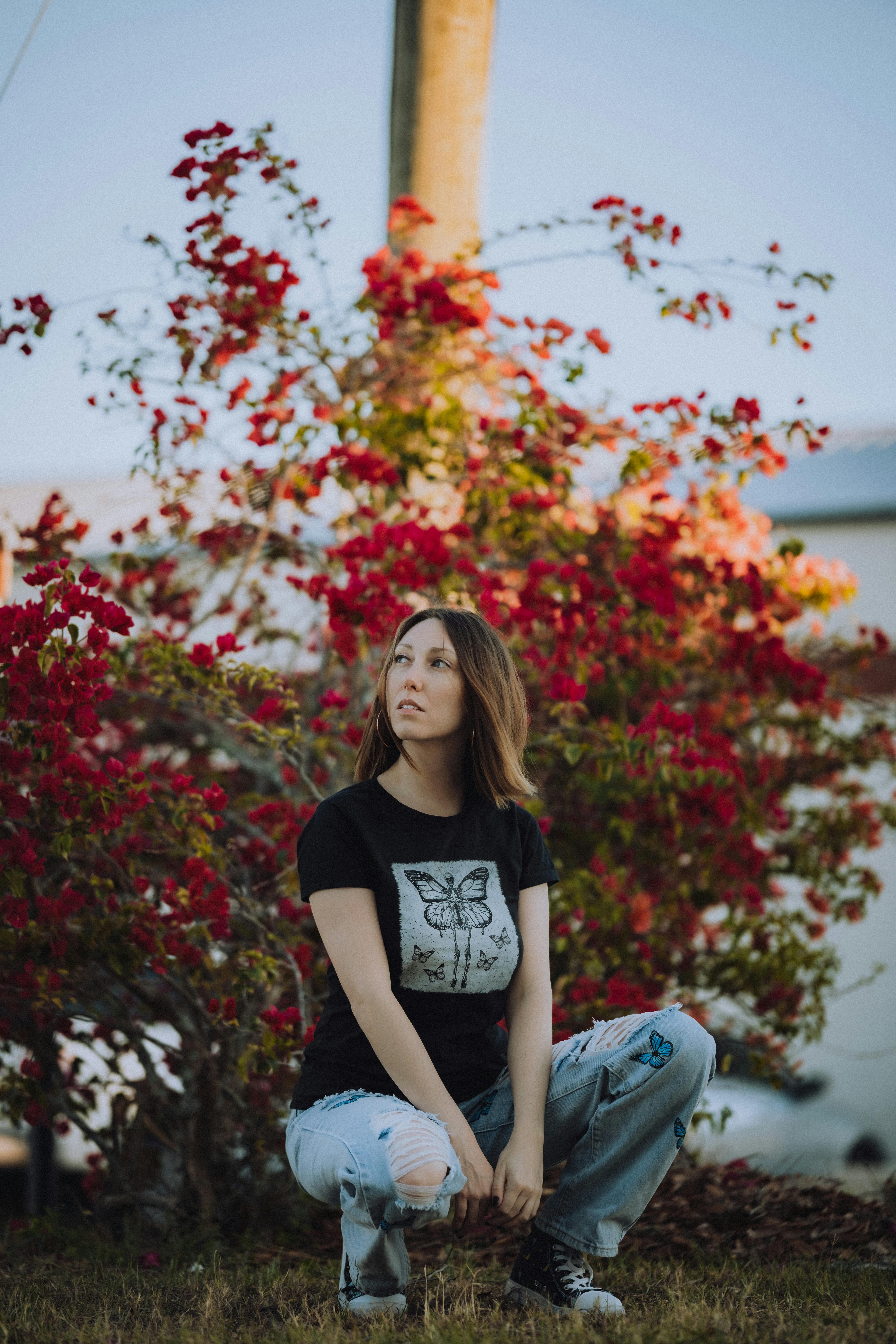 a woman crouching down in front of a bush