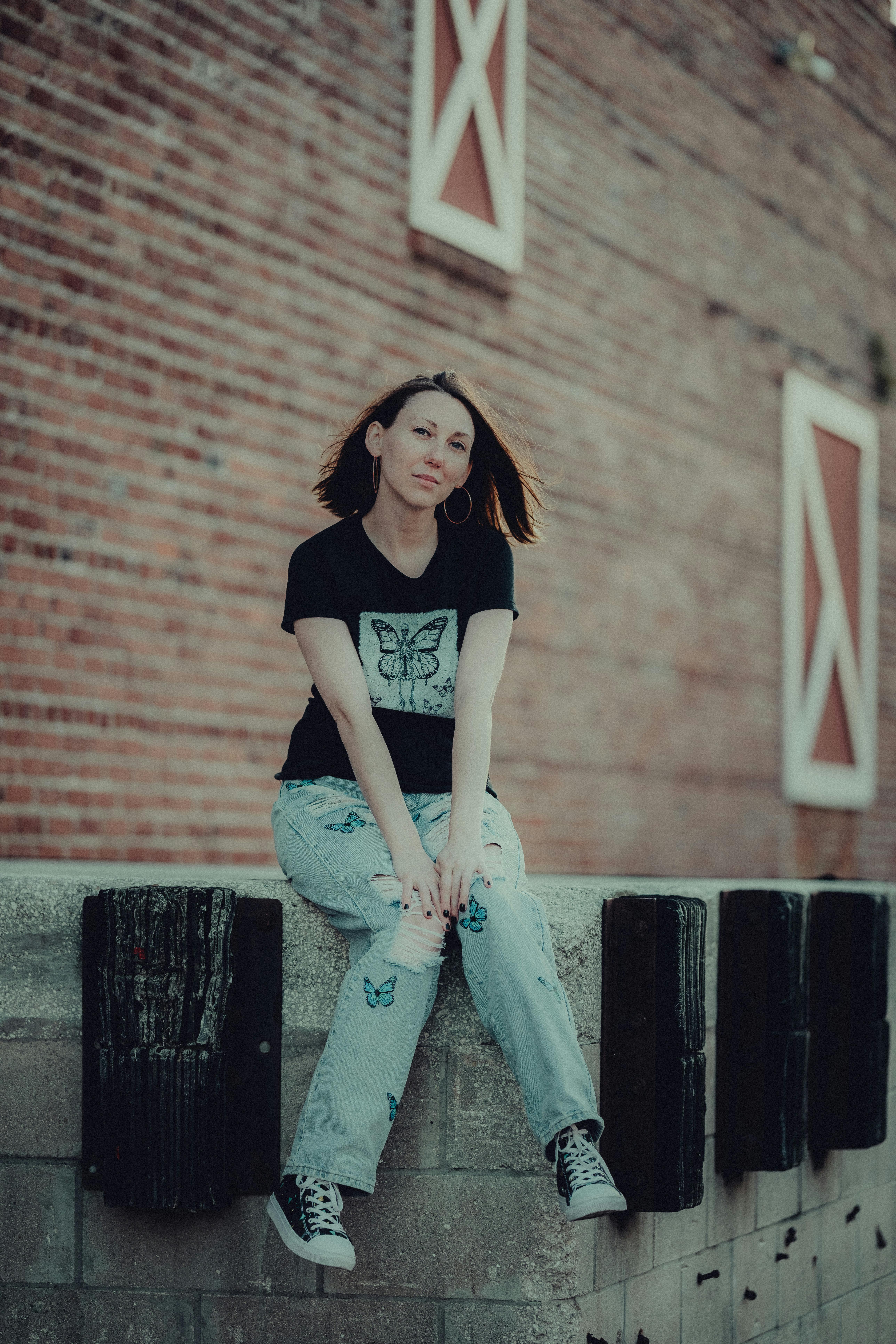 a girl sitting on a wall in front of a brick building