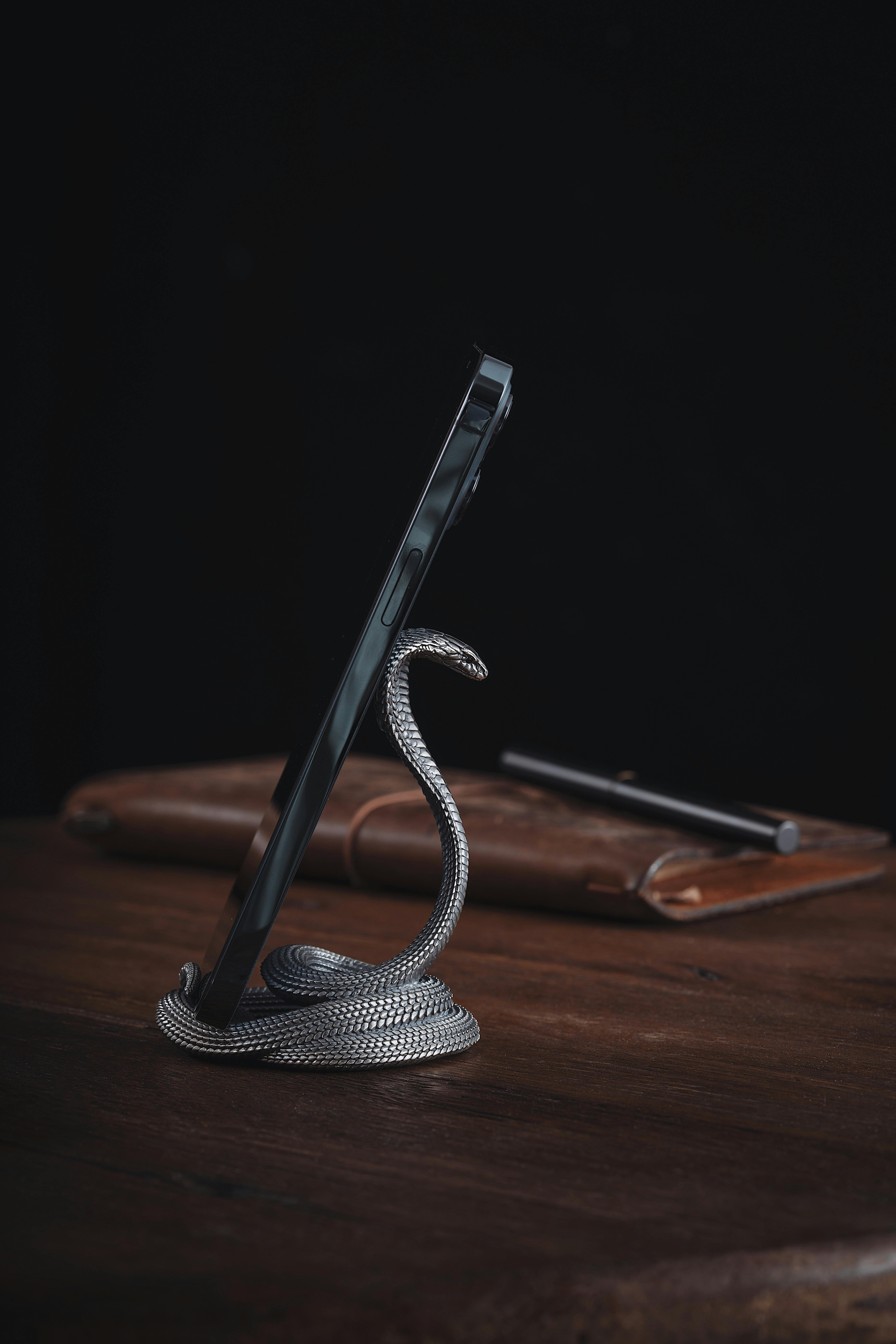 Free Stylish braided snake-shaped smartphone holder on a wooden desk, ideal for modern office setups. Stock Photo