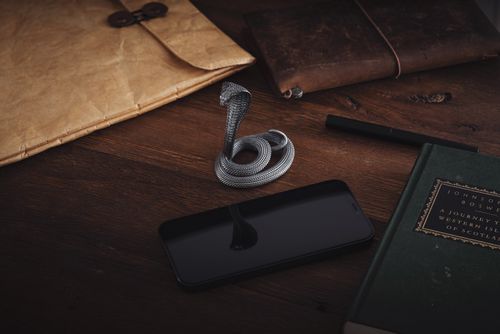 Free A vintage office desk layout featuring a cobra figurine, books, and a smartphone on a wooden surface. Stock Photo