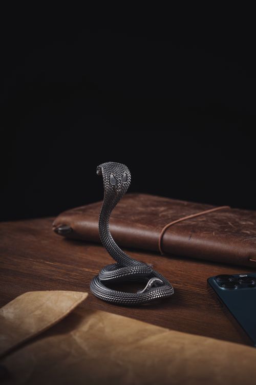 Free Artistic cobra figurine on a wooden desk with leather notebook and smartphone enhancing elegance. Stock Photo