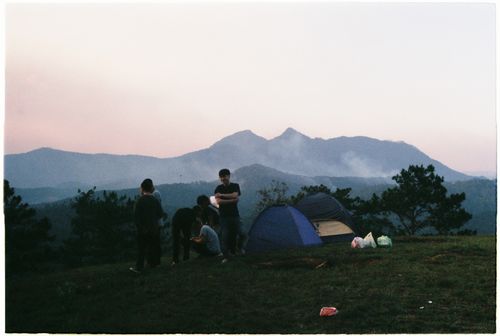 Free A group enjoying camping on a hill at twilight, surrounded by nature and mountains. Stock Photo