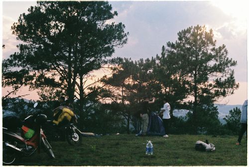 Free Group setting up camp with tents and motorbikes under evening sky Stock Photo