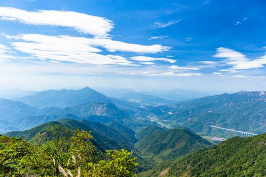 A breathtaking aerial view showcasing lush green mountains under a clear blue sky.