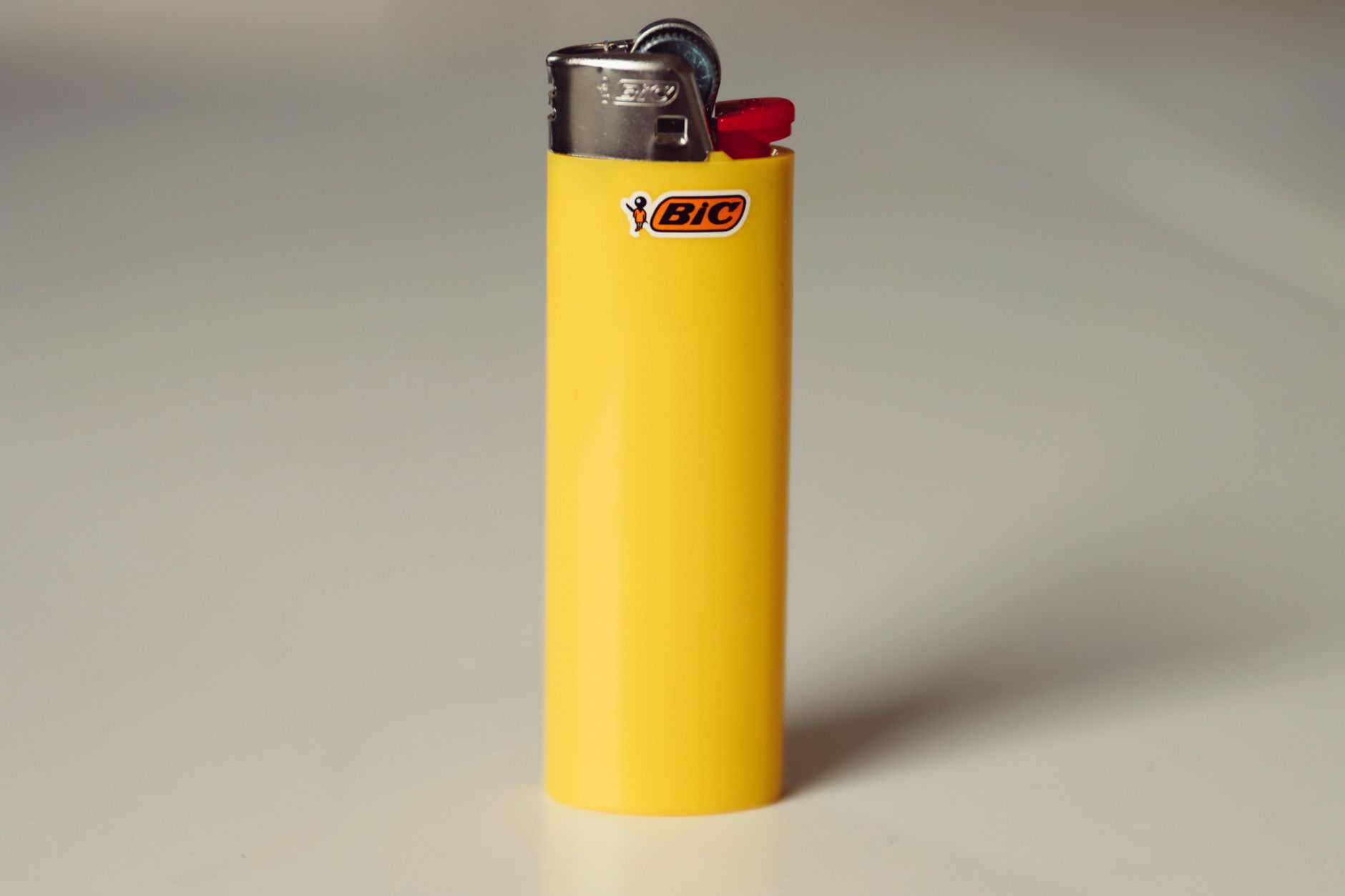 Close-up of a yellow Bic lighter on a white background for studio product showcase.