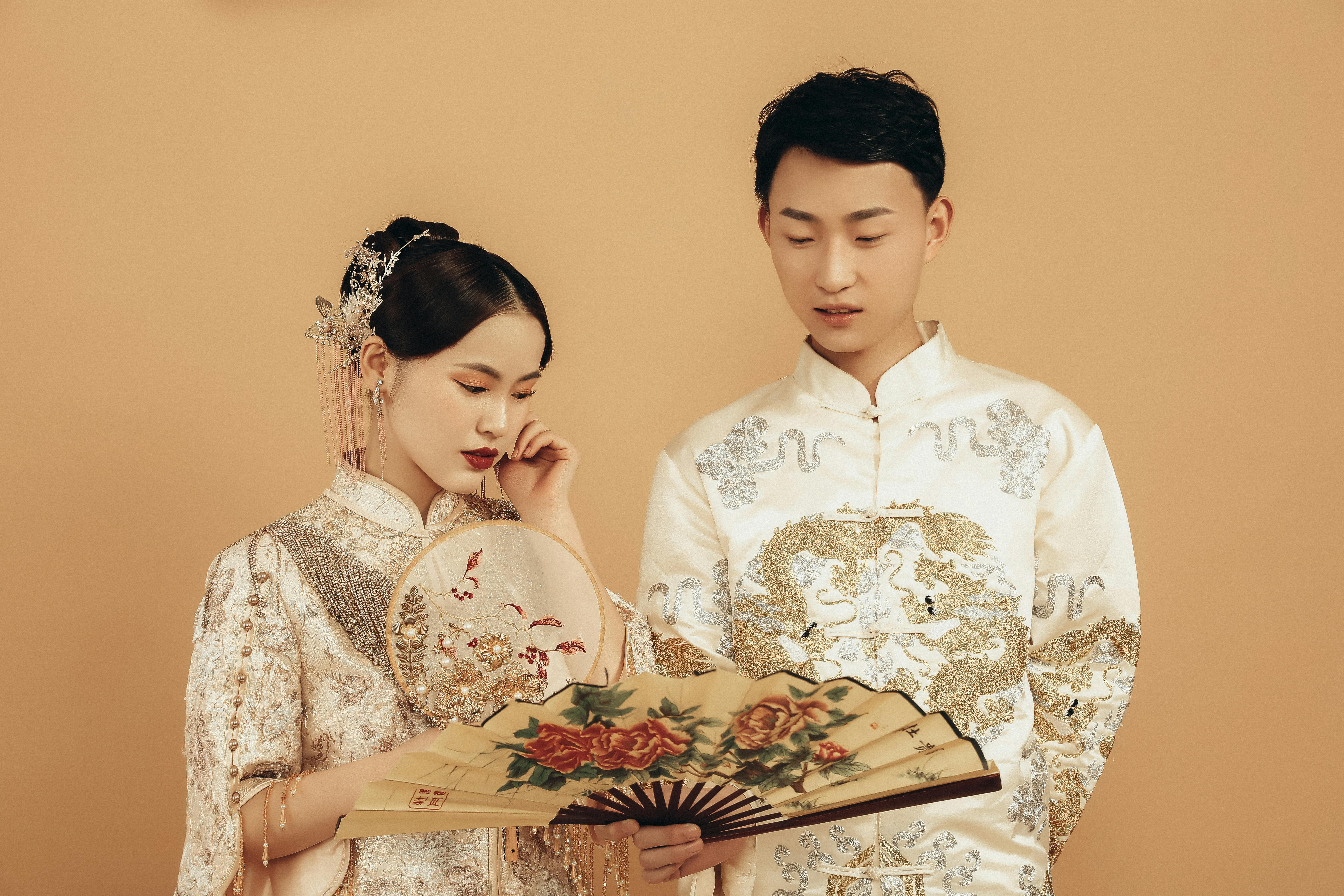Elegant portrait of a couple in traditional Asian wedding attire, showcasing cultural fashion.