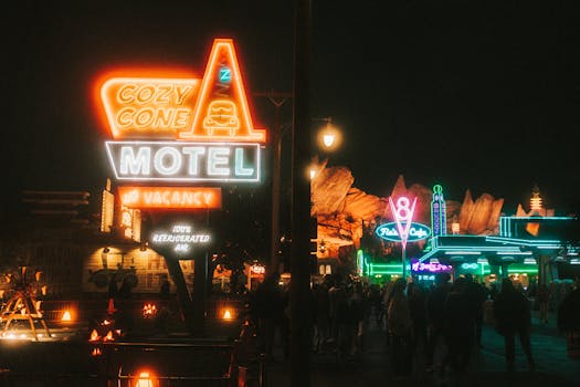 Vibrant nighttime scene of Cozy Cone Motel's neon lights attracting a crowd.