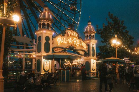 The iconic entrance of the Pixar Pal-A-Round ferris wheel illuminated at night in a vibrant amusement park setting.