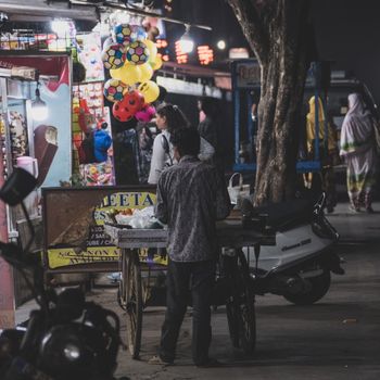 A bustling Mumbai street market at night with vendors and colorful balloons, capturing urban culture.