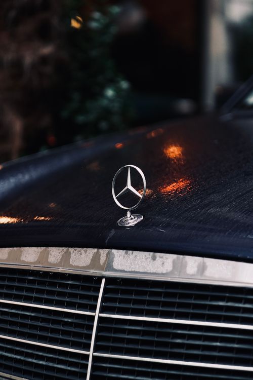 Free Close-up shot of a black car's wet hood featuring a prominent star emblem. Stock Photo