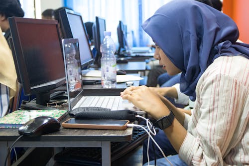 Young Woman Sitting in a Computer Classroom and Using a Laptop 