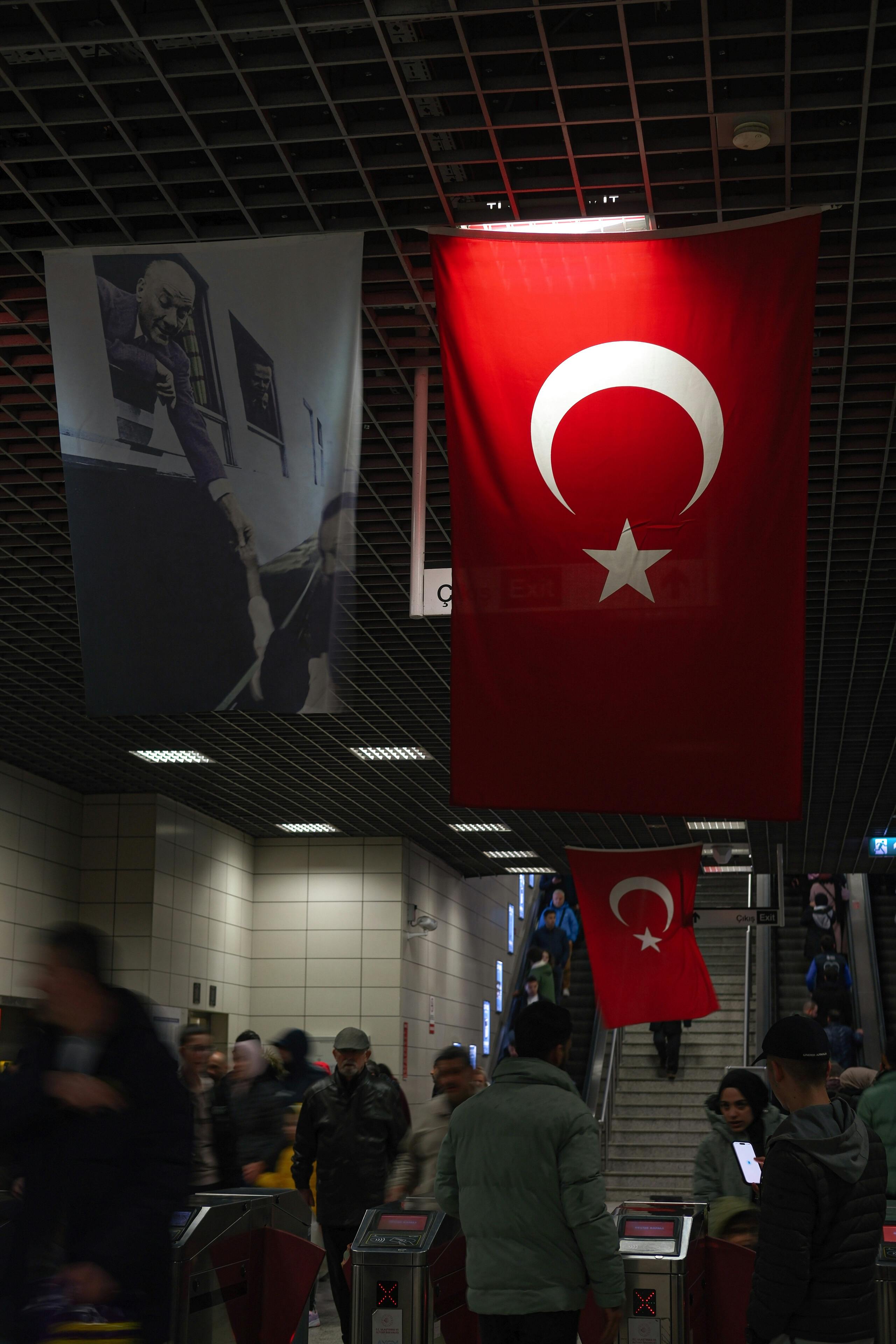 turkish flags hang from the ceiling of a train station