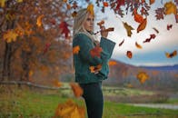 一位穿着毛衣的女子，在公园里被充满活力的秋叶环绕