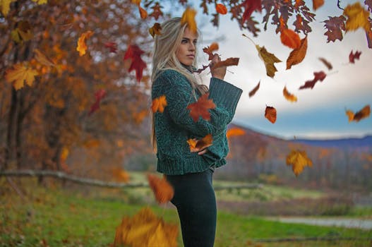 一位穿着毛衣的女子，在公园里被充满活力的秋叶环绕