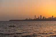 城市天际线前，日落时分的船上渔民剪影