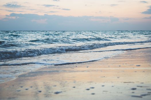 Serene beach scene at sunrise with gentle waves and pastel skies.