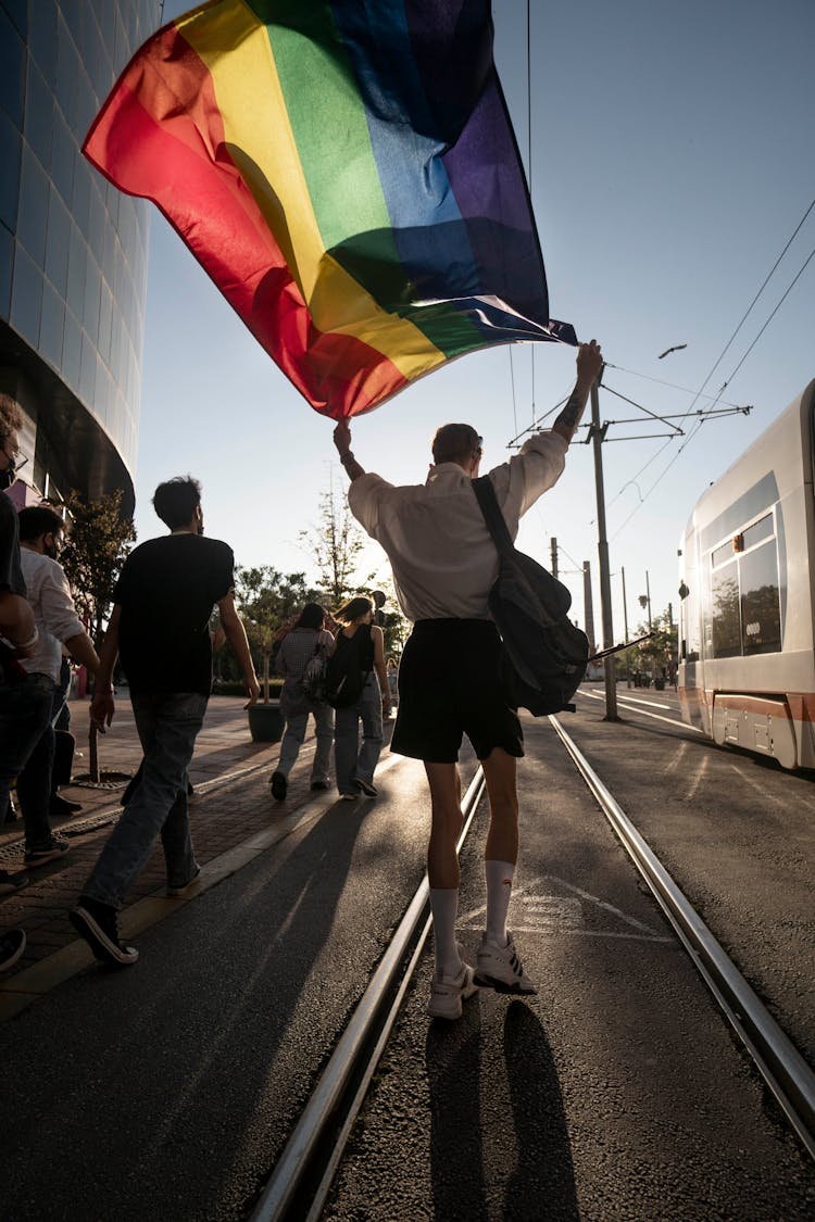 Man Walking With Colorful Flag On Street Festival