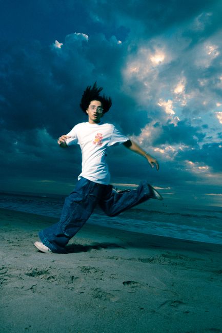 Vibrant image of a man running on a stormy beach at dusk, capturing movement and energy.