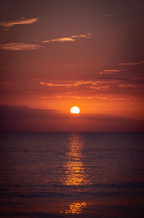 Free Breathtaking view of the sun setting over a calm sea, with vibrant red and orange hues painting the sky. Stock Photo