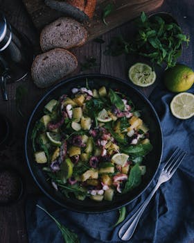 Gourmet octopus salad with potatoes, lime, and fresh herbs on a rustic table setting.