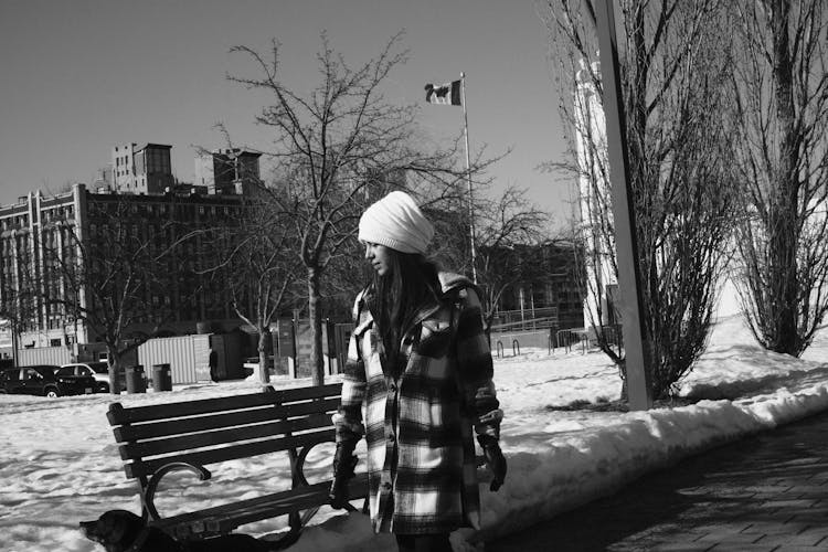 Young Woman In A Checkered Coat Walking In A Park In Winter 