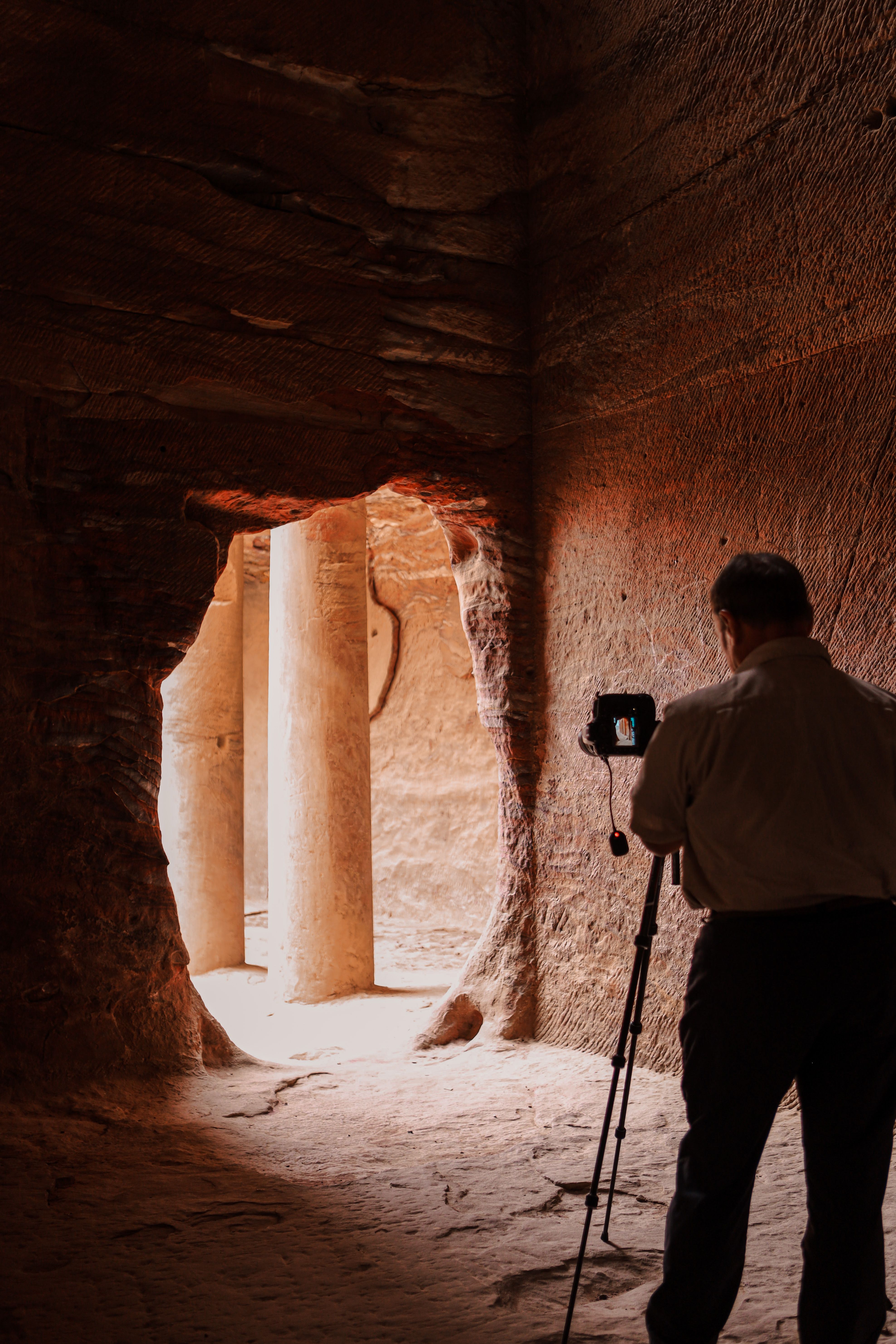 Photographer in Petra, Jordan, captures the ancient rock-carved architecture with a camera.