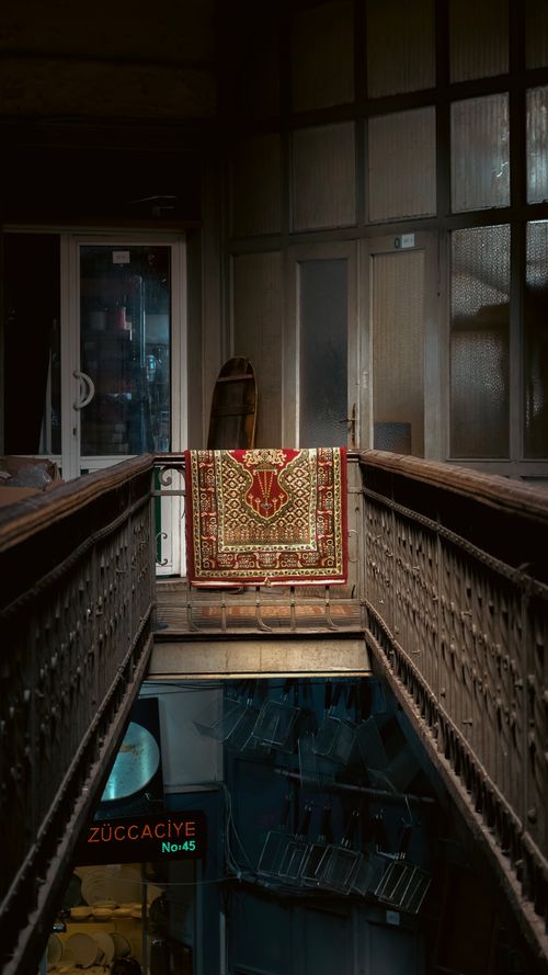 Free A vintage rug elegantly displayed in a traditional indoor hallway with decorative railings. Stock Photo