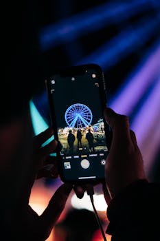 A vibrant nighttime shot of a Ferris wheel captured on a smartphone, highlighting nightlife.