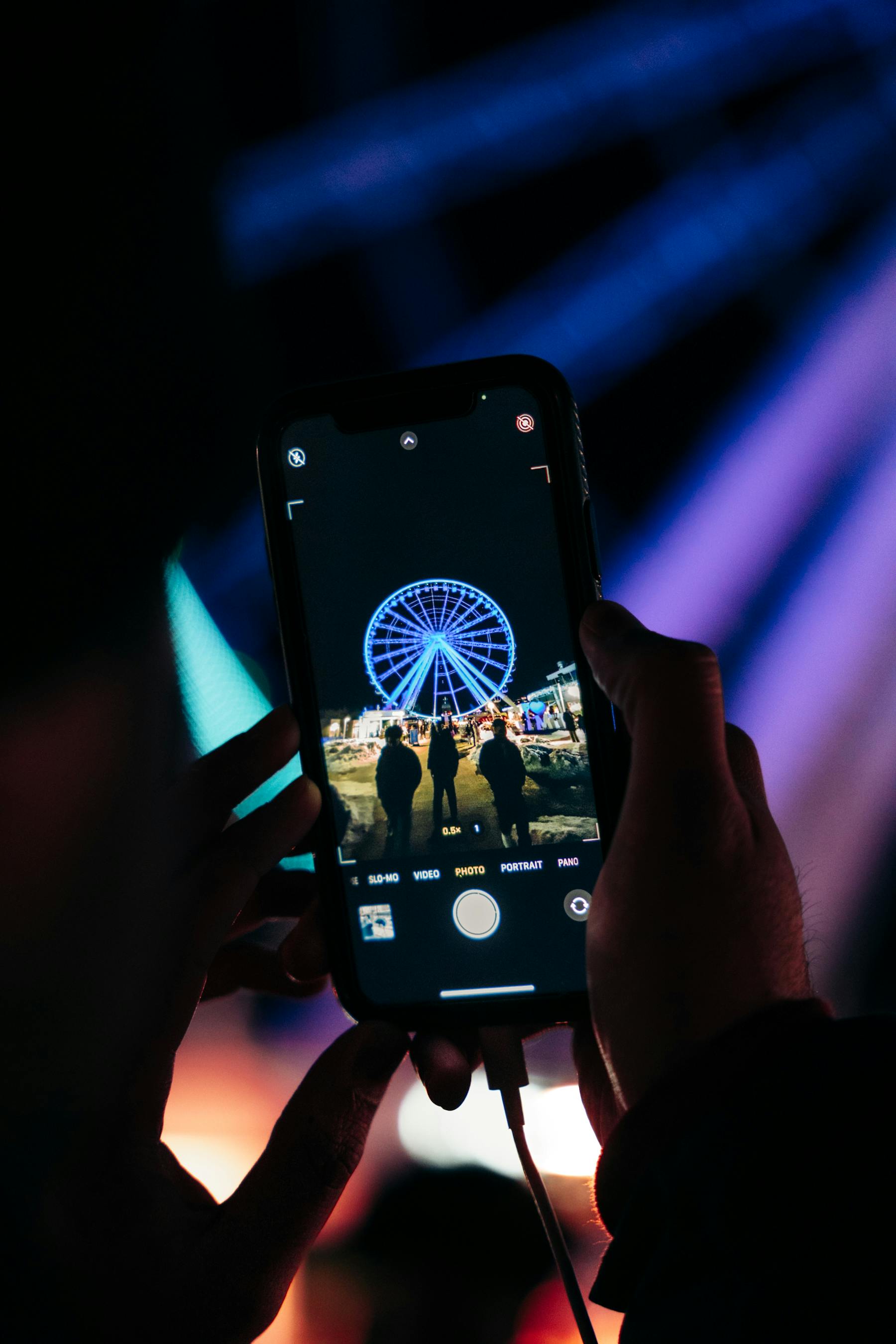 Free A vibrant nighttime shot of a Ferris wheel captured on a smartphone, highlighting nightlife. Stock Photo
