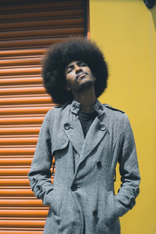 Man with Afro Hair in Coat Posing near Wall