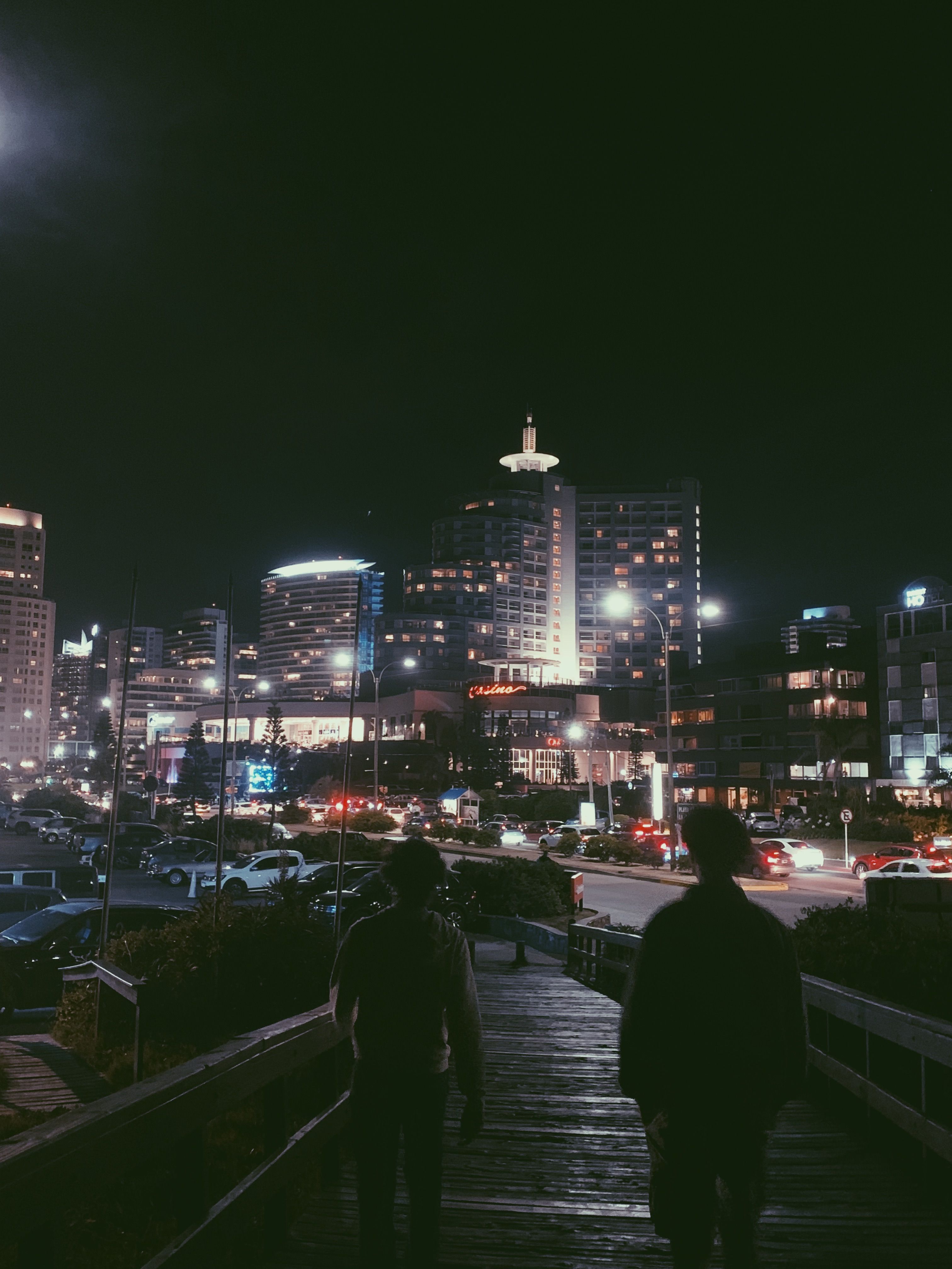 A bustling city street at night with illuminated buildings and people walking.