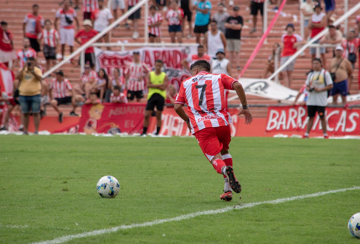 Footballer striking the ball under floodlights in a Meridian match kit