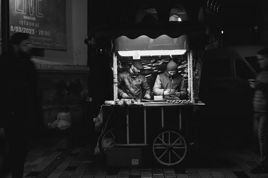 Monochrome photo of a street vendor scene in Istanbul at night, selling chestnuts.
