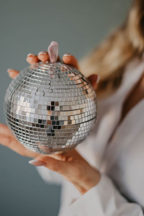 Free Close-up of woman holding a shiny disco ball, creating an elegant and reflective atmosphere. Stock Photo