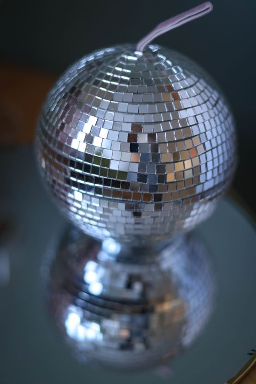 Free Close-up of a sparkling disco ball reflecting on a mirrored surface, ideal for party themes. Stock Photo