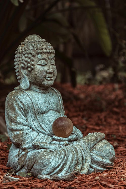 A buddha statue sitting in the middle of the ground