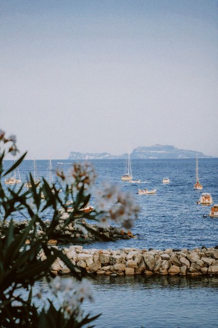 Idyllic coastal scene with sailboats and rocky shoreline, capturing tranquility.