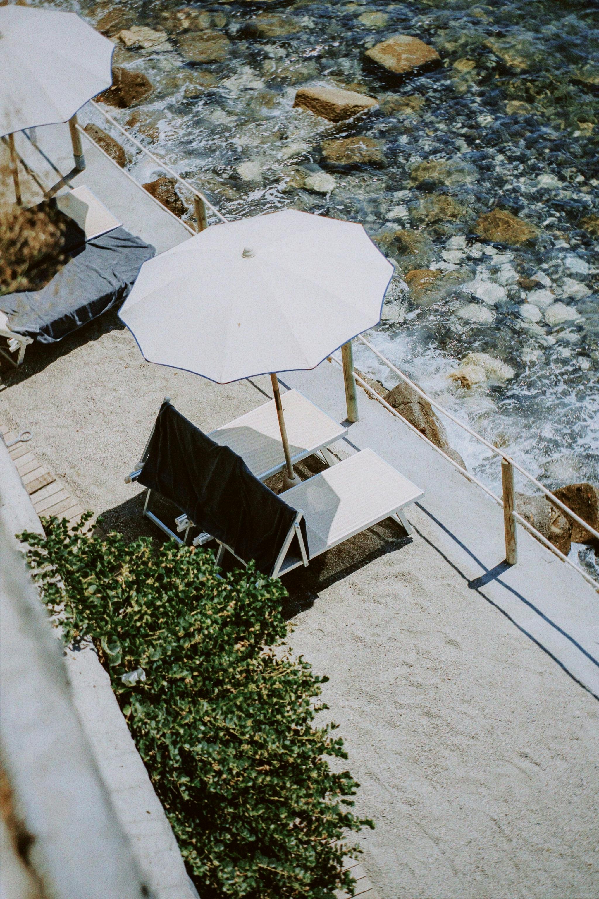 High angle view of beach loungers and umbrellas on a sunny rocky coastline