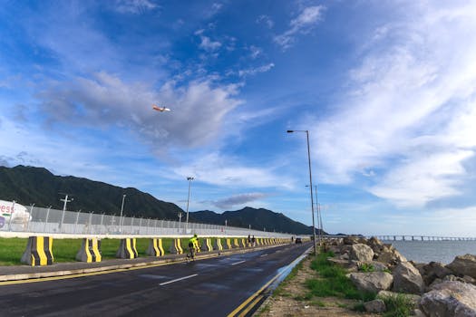 在充满活力的蓝天下，骑行者沿着香港九龙风景秀丽的道路骑行
