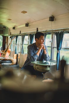 A man sits thoughtfully inside a vintage bus in San Lucas Sacatepéquez, Guatemala.