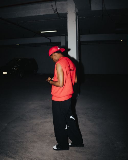 Free Young man in bright clothing looking down in dimly lit underground parking area. Stock Photo