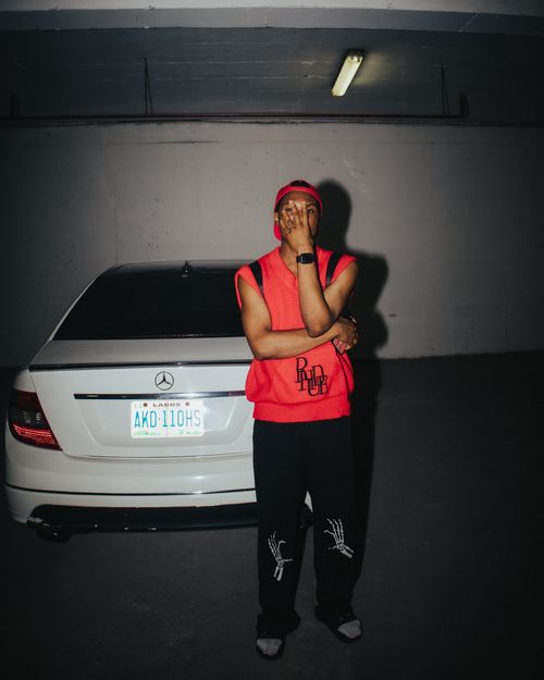 Free A stylish man poses with his car in a dimly lit parking garage, embracing urban fashion. Stock Photo