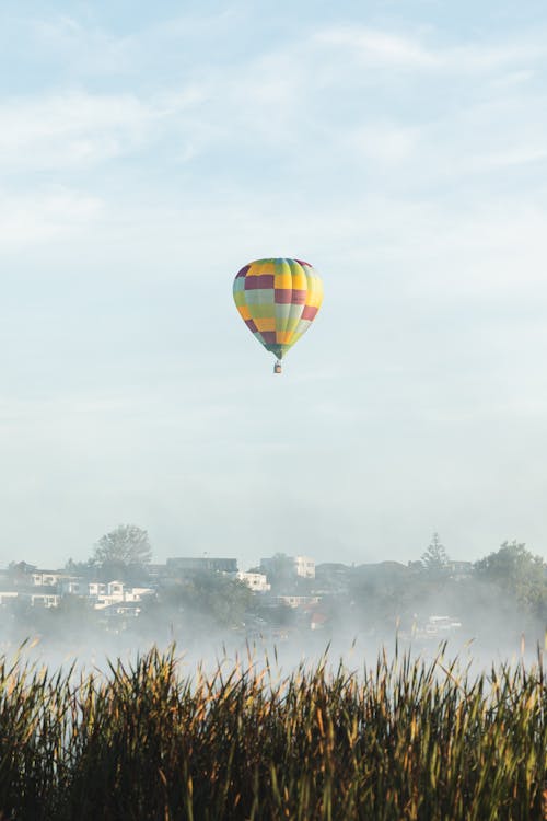 Checkered Hot Air Balloon Flying Above the Foggy City